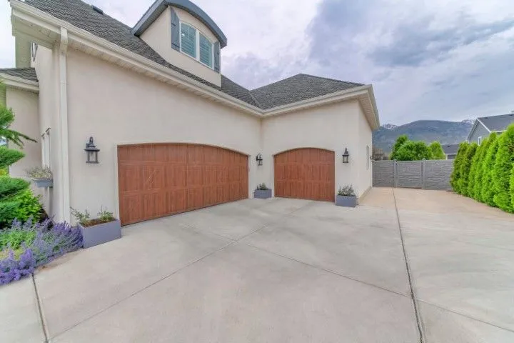 Two-car garage with brown doors, light stucco walls, concrete driveway, and a cloudy sky (Benton, Arkansas).